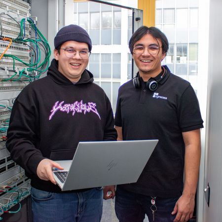 Bild zweier Kollegen fotografiert vor Serverkasten